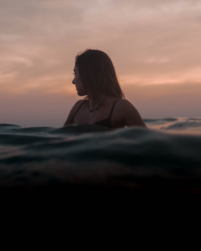 Woman enjoying the ocean during a serene sunset in Rio de Janeiro, Brazil.