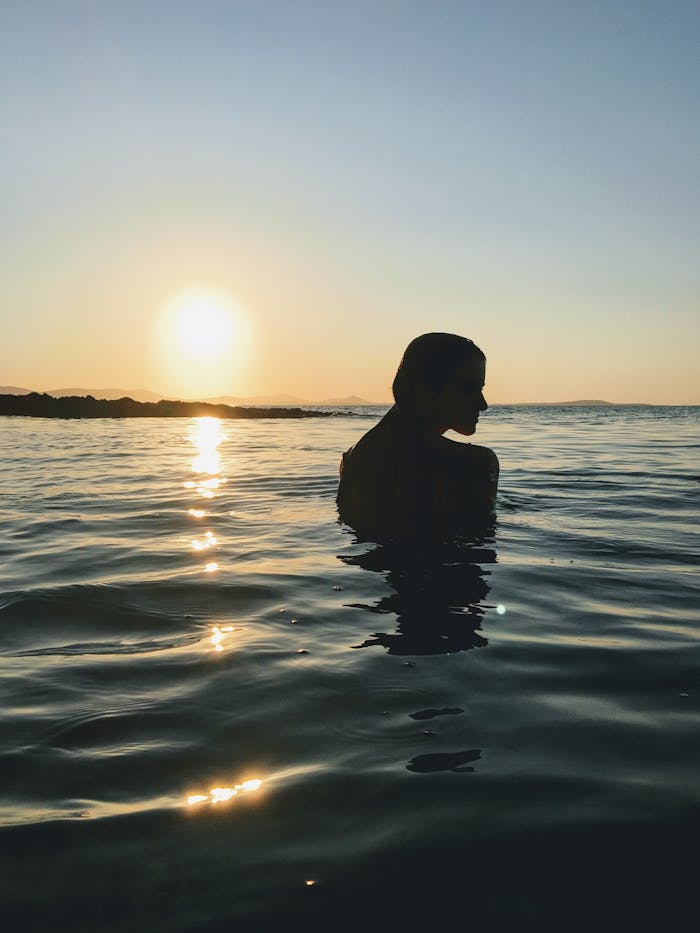 A woman enjoying a tranquil swim at sunset on a Naxos beach, Greece.